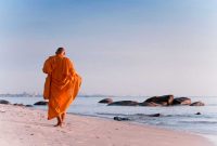 Seorang biksu berjalan di pantai di Distrik Hua Hin. (Foto: Pelopor.id/Unsplash/Thomas Oxford) 