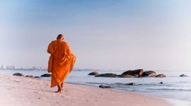 Seorang biksu berjalan di pantai di Distrik Hua Hin. (Foto: Pelopor.id/Unsplash/Thomas Oxford) 